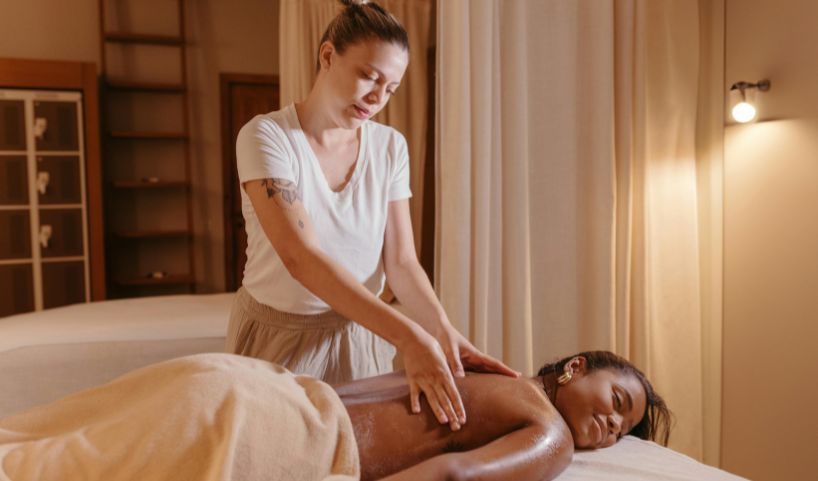 salle de massage cocooning où une femme profite d'une séance avec une masseuse bien-être